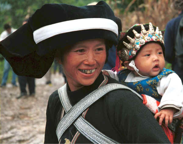 Side comb Miao woman and baby showing the baby's hat sporting protective white metal Buddhas - Long Dong village, De Wo township, Longlin country, Guangxi province 0010d32.jpg