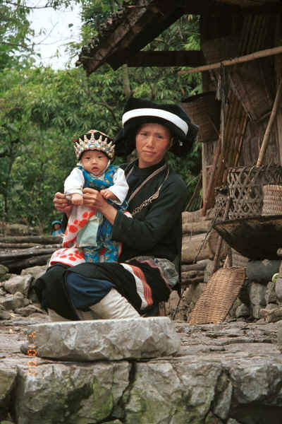 Side comb Miao woman and baby in their festival finery outside their house in Long Dong village, De Wo township, Longlin country, Guangxi province 0010e09.jpg