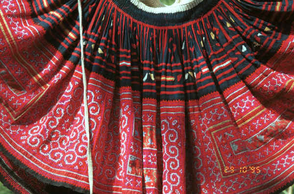 Detail of Green Hmong (Lai Chau province, northern Vietnam) woman's skirt showing the waist gathering, applied strips of red fabric and small triangles to the top border and cross-stitch with applied floral rectangles in the bottom border 9510f27.jpg